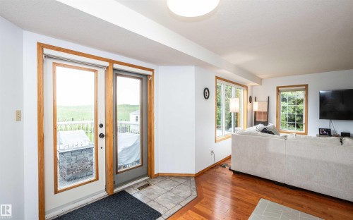 Patio doors with wood trim and glass panels opening to an outdoor deck with white railings - 5502 60 Avenue, Barrhead, AB - Indoor