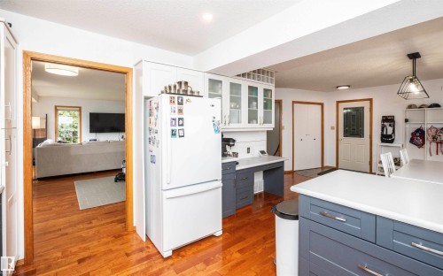 Kitchen featuring wood-finish flooring, two-tone cabinetry with glass-front uppers, and white countertops - 5502 60 Avenue, Barrhead, AB - Indoor Photo Showing Kitchen