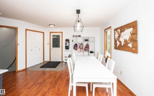 Bright dining area featuring wood-finish flooring, white walls, and a modern geometric pendant light fixture - 5502 60 Avenue, Barrhead, AB - Indoor Photo Showing Other Room