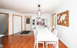Bright dining area featuring wood-finish flooring, white walls, and a modern geometric pendant light fixture - 