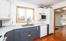 Kitchen featuring a two-tone cabinetry design with white upper cabinets and dark gray lower cabinets, white subway tile backsplash, and a light-colored countertop - 