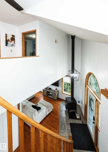 Vaulted ceiling entryway with a wood-burning stove, transom window, and wood-finish flooring - 5502 60 Avenue, Barrhead, AB - Indoor