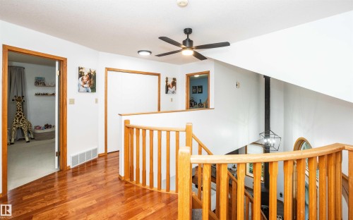Upper-level landing featuring polished wood-finish flooring, natural wood railings, and a contemporary ceiling fan - 5502 60 Avenue, Barrhead, AB - Indoor Photo Showing Other Room