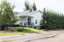 White siding exterior with a covered porch featuring black railings and an arched transom window - 
