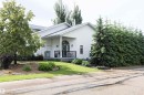 White siding exterior with a covered porch featuring black railings and an arched transom window - 5502 60 Avenue, Barrhead, AB  - Outdoor 