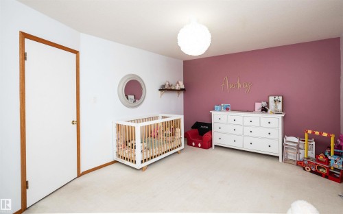 Room featuring a burgundy accent wall, white painted walls, and light-toned carpeting - 5502 60 Avenue, Barrhead, AB - Indoor Photo Showing Bedroom