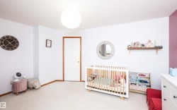 Carpeted room with a white door featuring wood trim, a circular ceiling light fixture, a built-in wall shelf, and a color-blocked accent wall - 