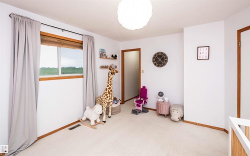 Carpeted room featuring a white ceiling and walls with wood trim - 5502 60 Avenue, Barrhead, AB - Indoor