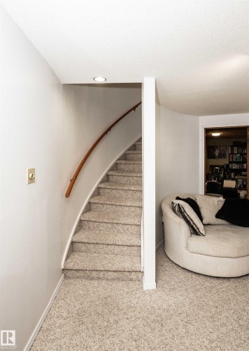 Curved staircase with a light wood handrail, recessed ceiling lighting, and neutral-toned carpeting throughout - 5502 60 Avenue, Barrhead, AB - Indoor Photo Showing Other Room