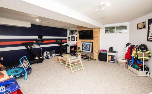 Spacious finished lower level featuring wall-to-wall carpeting, track lighting, and a feature wall with horizontal stripe detailing - 5502 60 Avenue, Barrhead, AB - Indoor Photo Showing Other Room