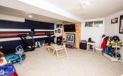 Spacious finished lower level featuring wall-to-wall carpeting, track lighting, and a feature wall with horizontal stripe detailing - 