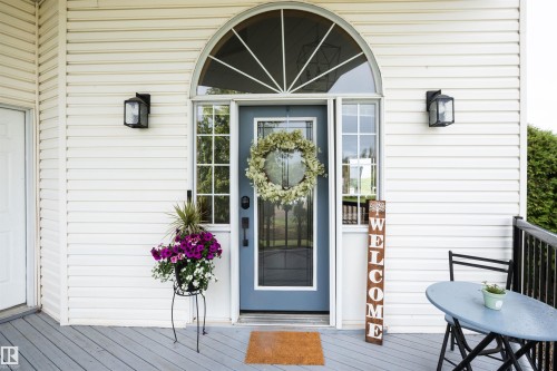Entryway featuring a light blue door with sidelights, an arched transom window, and white horizontal siding - 5502 60 Avenue, Barrhead, AB - Outdoor With Deck Patio Veranda With Exterior
