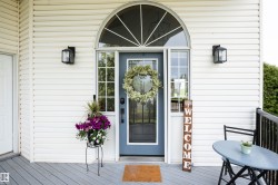 Entryway featuring a light blue door with sidelights, an arched transom window, and white horizontal siding - 