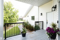 Covered front porch featuring a white entry door with black hardware, white siding, black exterior lanterns, and black railing - 