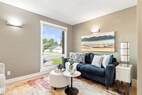 Neutral wall paint, wood-finish flooring, white window trim, and wall-mounted lighting fixtures - 14307 50 Avenue Nw, Edmonton, AB 