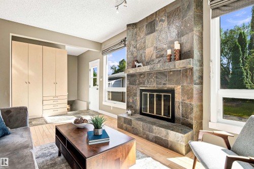 Stone-clad fireplace with a built-in mantel, integrated firebox, and glass doors - 14307 50 Avenue Nw, Edmonton, AB 