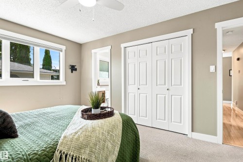 Recessed window with white trim, bi-fold closet doors, and light-colored carpeting - 14307 50 Avenue Nw, Edmonton, AB 