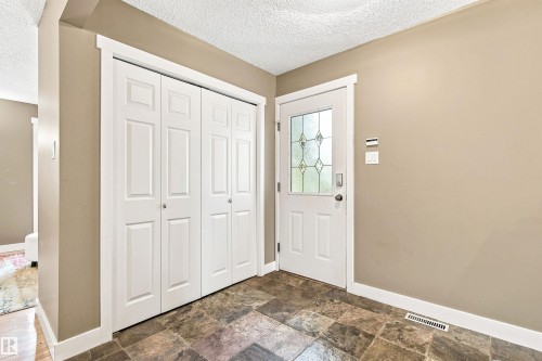 Entryway featuring tiled flooring, a white paneled door with leaded glass, and bi-fold closet doors - 14307 50 Avenue Nw, Edmonton, AB 