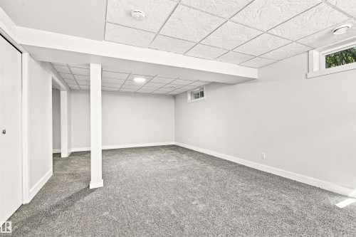 Spacious room with gray carpeting, white walls, and a white grid ceiling - 14307 50 Avenue Nw, Edmonton, AB 