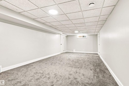 Spacious room with gray carpeting, white painted walls, and a drop-tile ceiling with recessed lighting - 14307 50 Avenue Nw, Edmonton, AB 