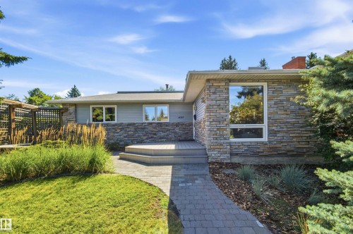 Exterior featuring stone veneer and siding, a multi-tiered entry deck, and a stone paver walkway - 14307 50 Avenue Nw, Edmonton, AB 