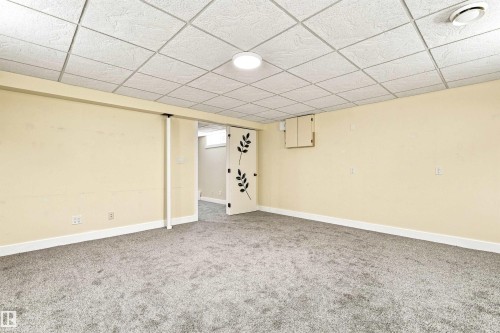 Spacious room featuring neutral carpeting and a drop ceiling with integrated lighting - 14307 50 Avenue Nw, Edmonton, AB 