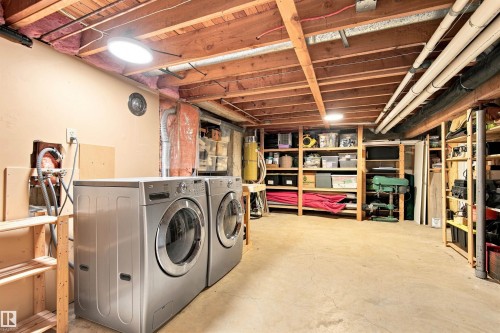 Basement utility area with exposed wood ceiling beams, concrete flooring, and built-in wood shelving for storage - 14307 50 Avenue Nw, Edmonton, AB 
