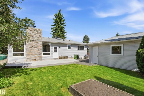 Expansive backyard featuring a manicured lawn, a raised garden bed, and a concrete patio - 14307 50 Avenue Nw, Edmonton, AB 