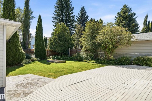 Expansive backyard featuring a spacious composite deck, manicured lawn, stamped concrete patio, and mature landscaping - 14307 50 Avenue Nw, Edmonton, AB 