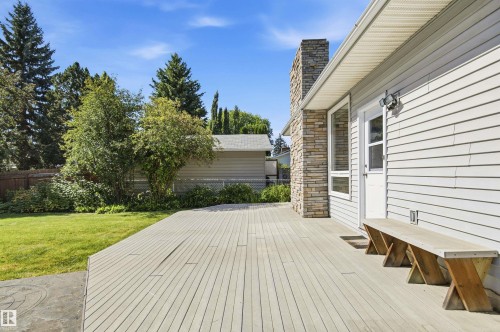Spacious outdoor deck with a textured surface, stone-clad chimney, and horizontal siding - 14307 50 Avenue Nw, Edmonton, AB 