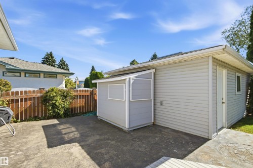 Concrete patio featuring a wood privacy fence and mature landscaping - 14307 50 Avenue Nw, Edmonton, AB 