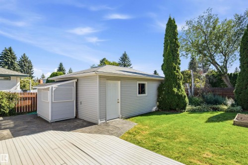 Expansive backyard featuring a manicured lawn, an attached shed with siding, and an additional smaller shed - 14307 50 Avenue Nw, Edmonton, AB 
