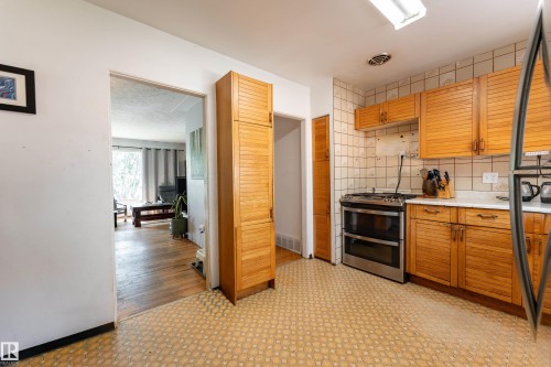 Kitchen featuring tile flooring, wood-finish cabinetry, and a stainless steel oven - 14906 76 Avenue Nw, Edmonton, AB 