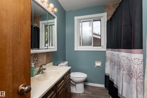 Bathroom featuring a single vanity, a toilet, a window, and a shower area - 14906 76 Avenue Nw, Edmonton, AB 
