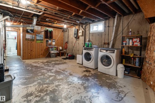 Concrete flooring with exposed ceiling joists, wood paneling, and a small window - 14906 76 Avenue Nw, Edmonton, AB 