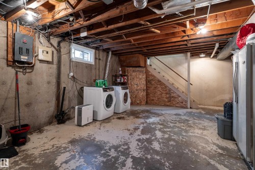 Unfinished basement featuring exposed wood joists, a small window, concrete walls, and a utility staircase - 14906 76 Avenue Nw, Edmonton, AB 