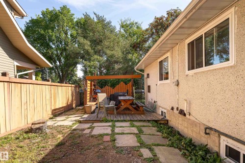 Wood deck with a pergola structure, concrete paver pathway, and wood privacy fencing - 14906 76 Avenue Nw, Edmonton, AB 