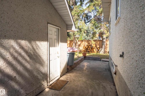 Concrete patio area with a privacy fence and mature trees - 14906 76 Avenue Nw, Edmonton, AB 