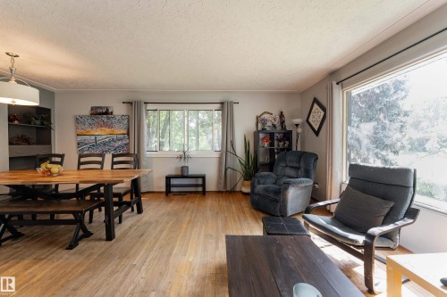 Hardwood-finish flooring throughout, a built-in shelving unit, and multiple windows providing natural light - 14906 76 Avenue Nw, Edmonton, AB 