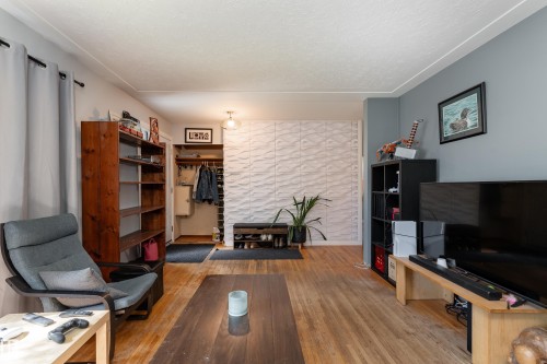Wood-finish flooring throughout, featuring a textured accent wall, exposed shelving, and a built-in coat rack - 14906 76 Avenue Nw, Edmonton, AB 