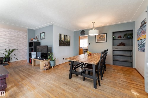 Wood-finish flooring, accent wall with textured paneling, recessed shelving, and a drum pendant light fixture - 14906 76 Avenue Nw, Edmonton, AB 
