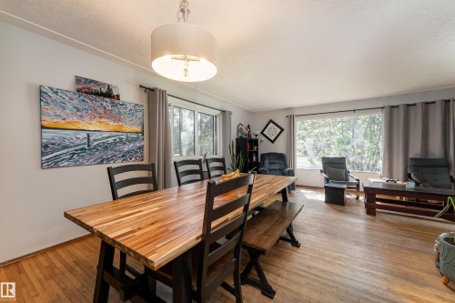 Wood-finish flooring throughout, with a drum pendant light fixture illuminating the dining area - 14906 76 Avenue Nw, Edmonton, AB 