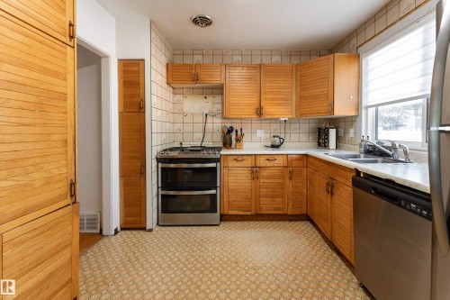 Kitchen featuring wood-finish cabinetry, tile backsplash, a stainless steel range, and a stainless steel dishwasher - 14906 76 Avenue Nw, Edmonton, AB 