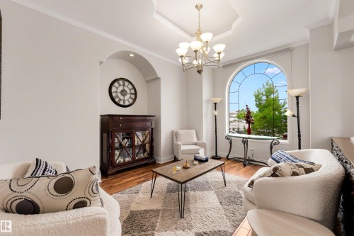 Arched window with gridded panes, coffered ceiling, chandelier lighting, recessed wall niche, and wood-finish flooring - 282 Ozerna Road Nw, Edmonton, AB 