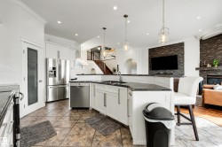 Kitchen featuring a center island with dark countertops, white cabinetry, stainless steel appliances, and tile flooring - 