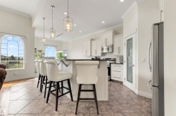 Kitchen island with dark countertop, white cabinetry, integrated stainless steel appliances, tile flooring, and arched windows - 