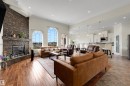 Open-concept living space featuring high ceilings, a stone-clad fireplace, and arched windows - 282 Ozerna Road Nw, Edmonton, AB 