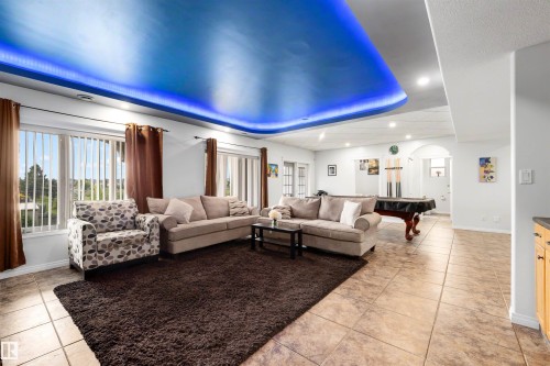 Recessed ceiling with integrated blue lighting, tile flooring, window with vertical blinds, and a built-in archway - 282 Ozerna Road Nw, Edmonton, AB 