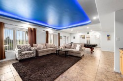 Recessed ceiling with integrated blue lighting, tile flooring, window with vertical blinds, and a built-in archway - 
