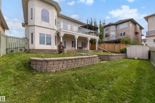 Tiered retaining walls, a covered lower patio, and an upper balcony with glass panel railing - 282 Ozerna Road Nw, Edmonton, AB 